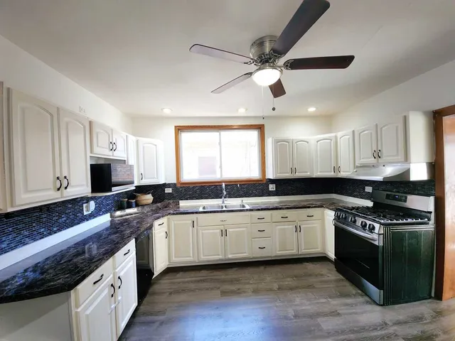 a large kitchen with stainless steel appliances granite countertop a stove sink and cabinets