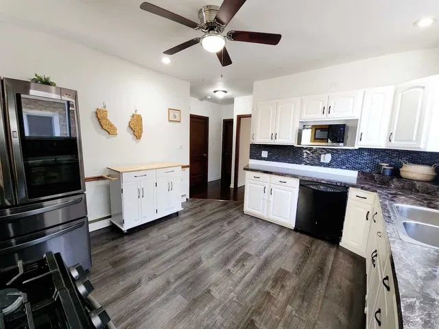 a kitchen with stainless steel appliances a stove top oven a sink a refrigerator cabinets and a dining table