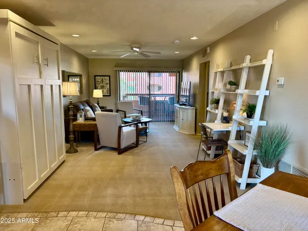 a living room with couches kitchen view and a refrigerator