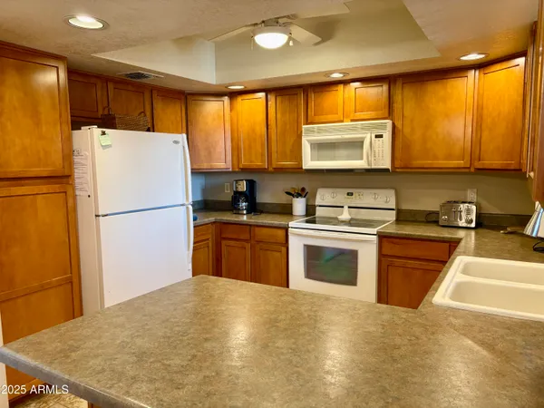 a kitchen with granite countertop a refrigerator sink stove and wooden cabinets
