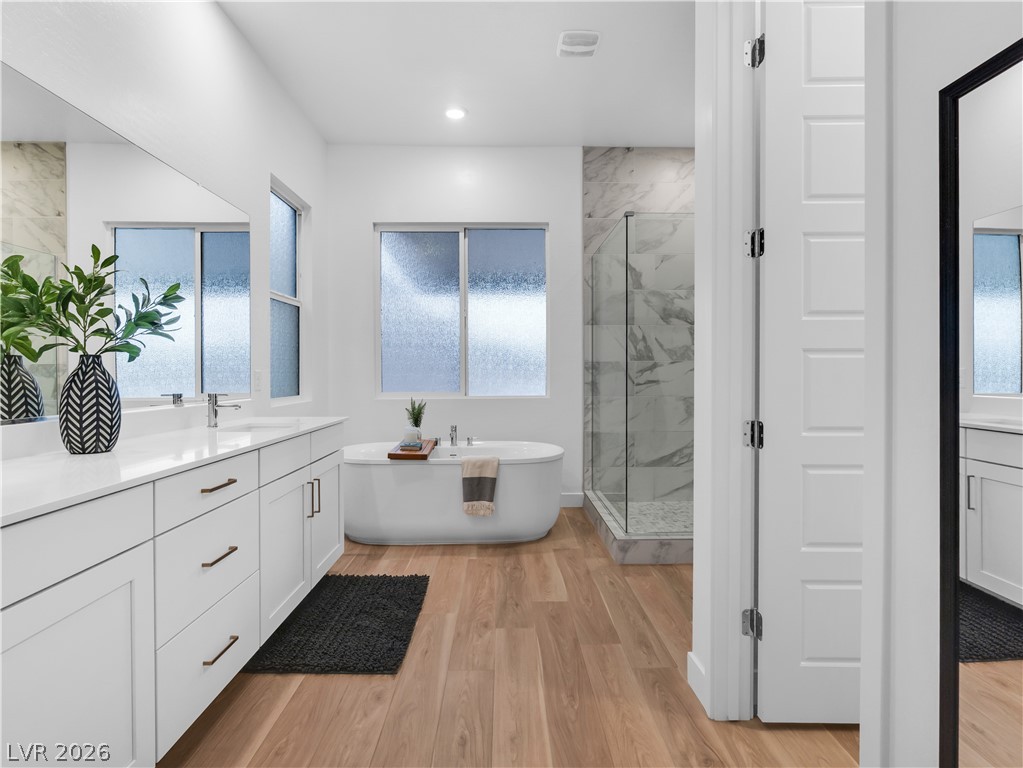153 Montevallo Bnd Street Henderson, NV 89015 - Photo 30 of 65 Bathroom with vanity, a marble finish shower, light wood-style floors, and a freestanding tub