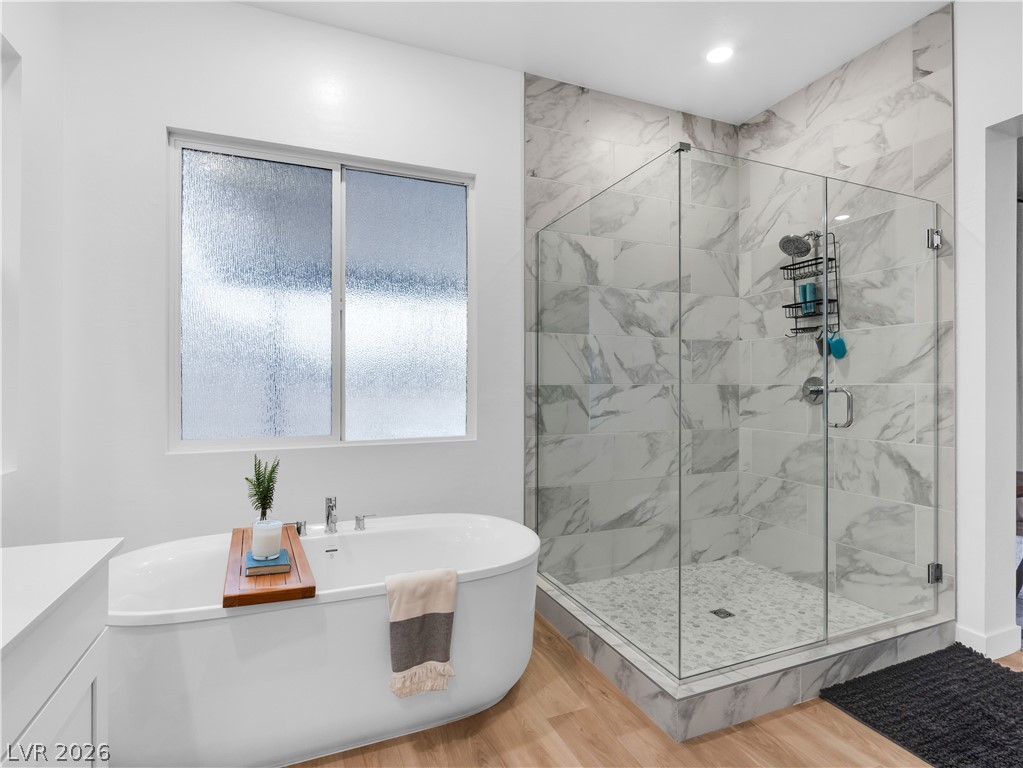 153 Montevallo Bnd Street Henderson, NV 89015 - Photo 31 of 65 Bathroom featuring a marble finish shower, light wood-style floors, a soaking tub, and vanity