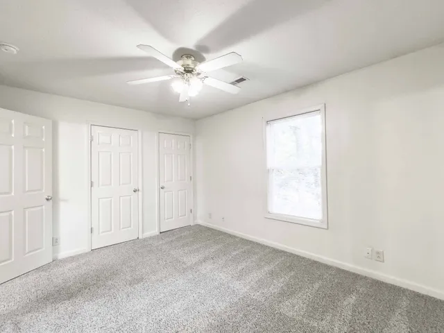 an empty room with windows and fan