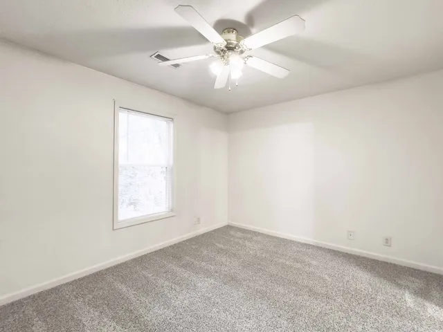 an empty room with windows and fan