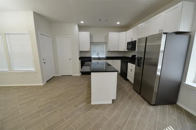 a kitchen with a refrigerator a stove top oven and white cabinets