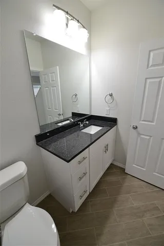 a spacious bathroom with a granite countertop sink and a toilet