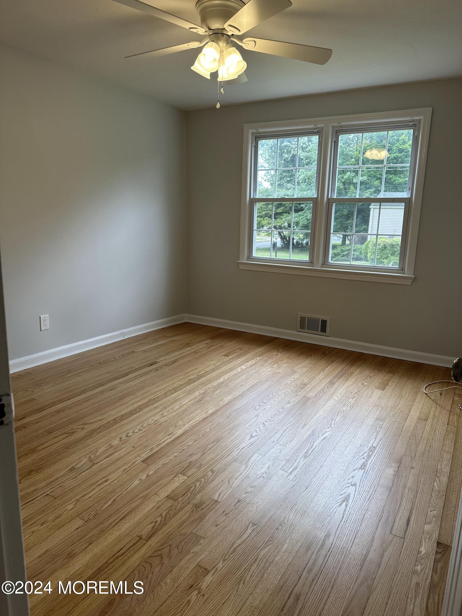 57 Kings Road Little Silver, NJ 07739 - Photo 15 of 22 an empty room with wooden floor chandelier fan and windows