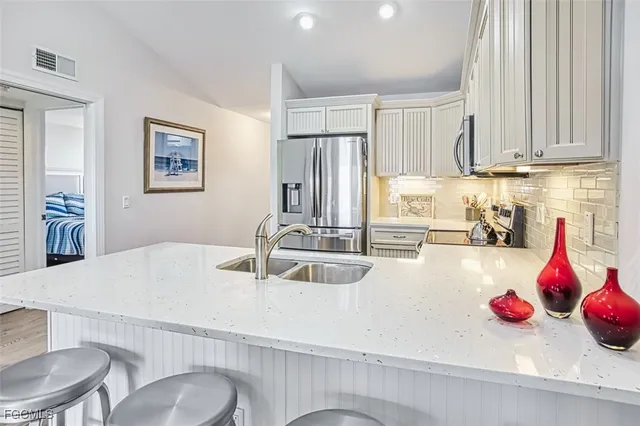 a kitchen with stainless steel appliances granite countertop a dining table chairs and white cabinets