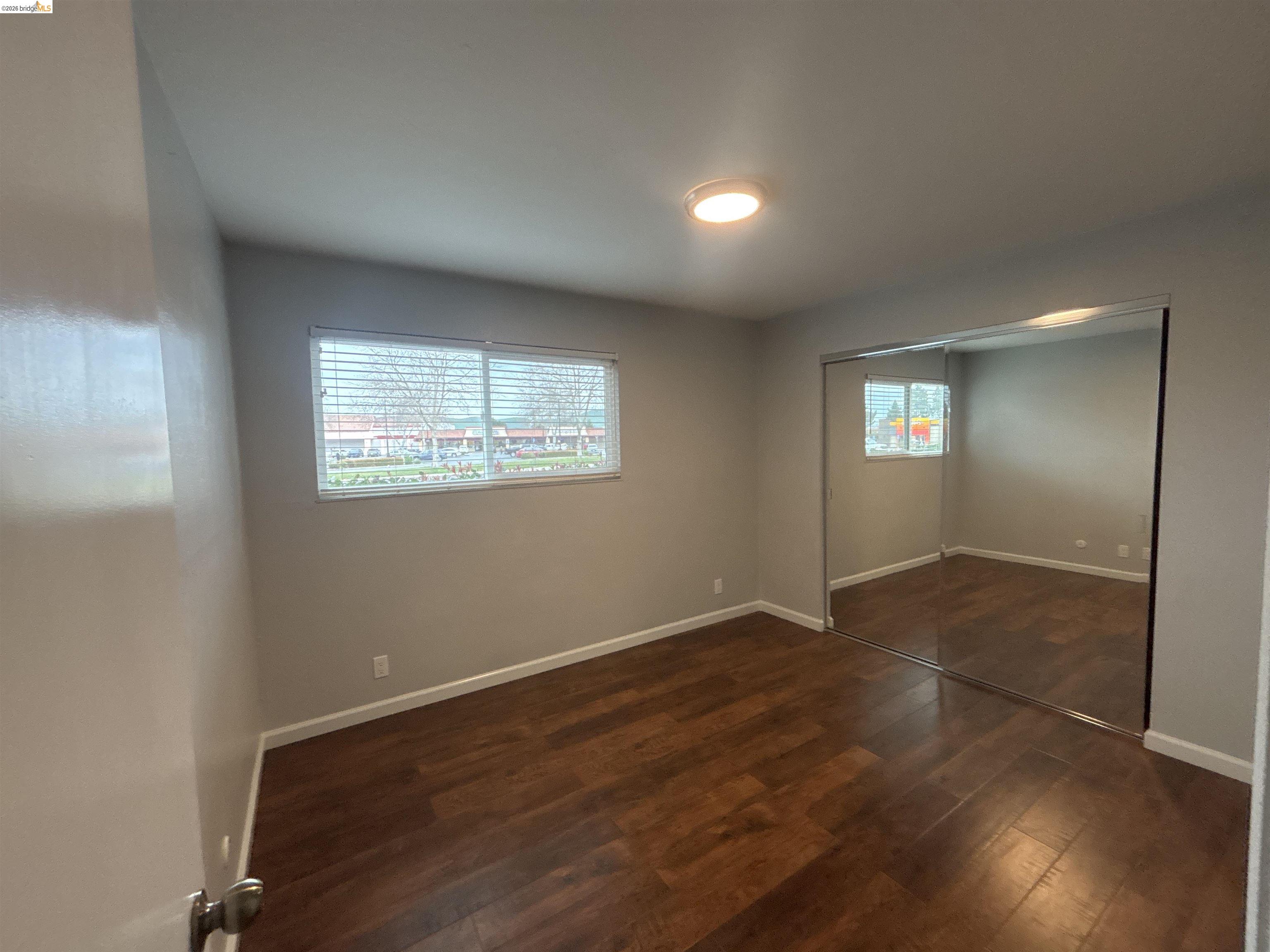 4462 Clayton Road, Unit A Concord, CA 94521 - Photo 7 of 11 an empty room with wooden floor and windows