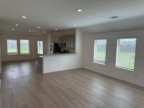 an empty room with wooden floor and windows