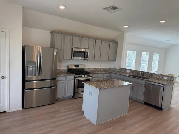 a kitchen with stainless steel appliances granite countertop a refrigerator stove and wooden cabinets