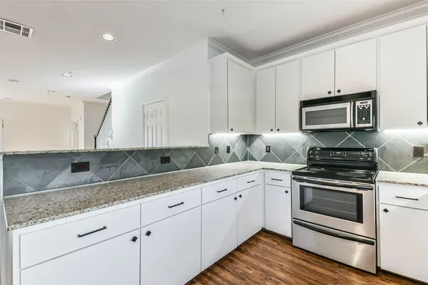 a kitchen with granite countertop white cabinets and appliances