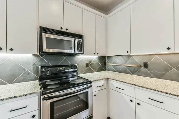 a kitchen with granite countertop a stove microwave and cabinets