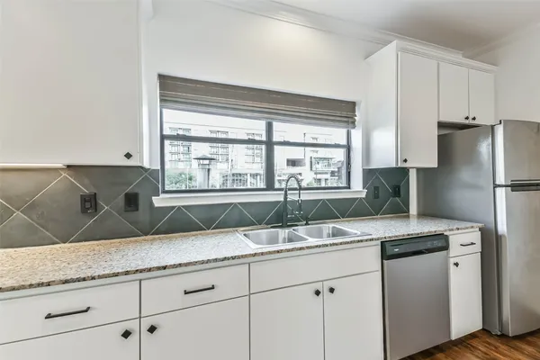 a kitchen with granite countertop a sink and a refrigerator