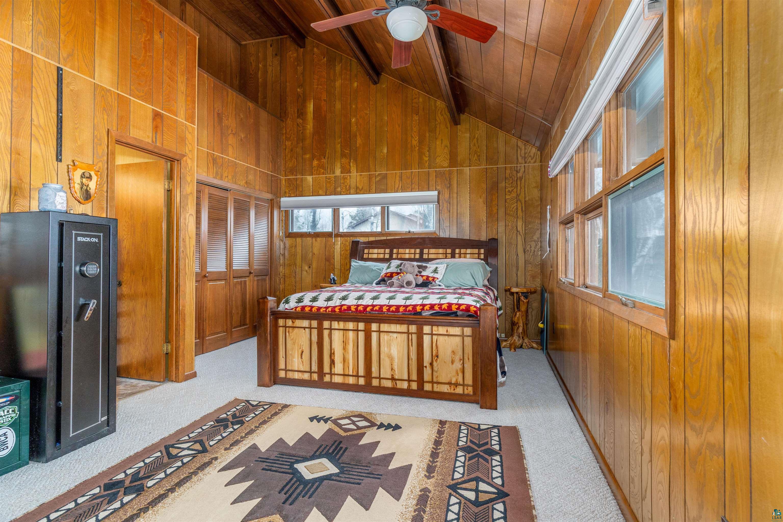 2641 Priest Point Road Ely, MN 55731 - Photo 17 of 38 Bedroom with wooden walls, light carpet, ceiling fan, and a high wooden beamed ceiling