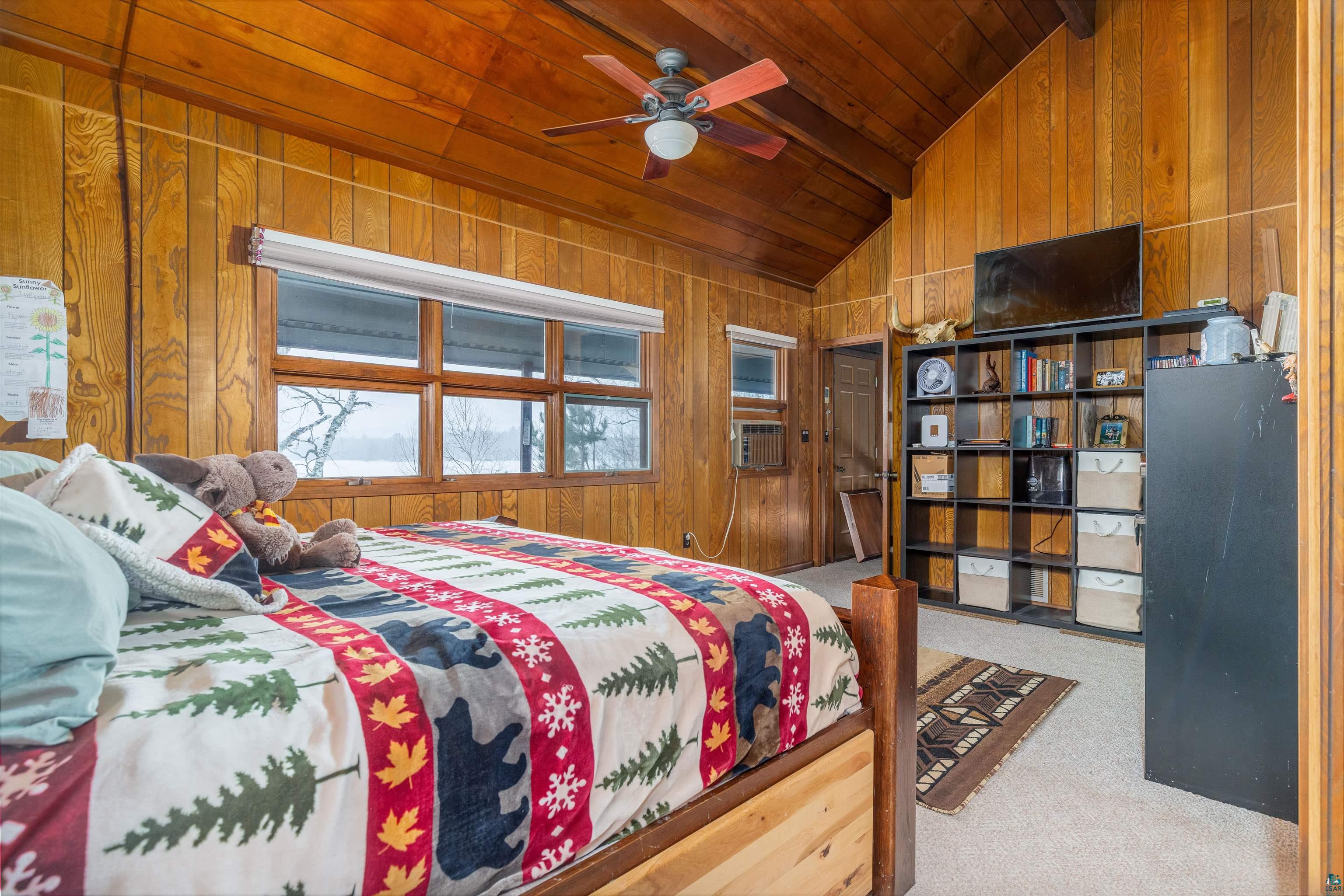 2641 Priest Point Road Ely, MN 55731 - Photo 18 of 38 Bedroom featuring wooden walls, light colored carpet, lofted ceiling with beams, ceiling fan, and wood ceiling