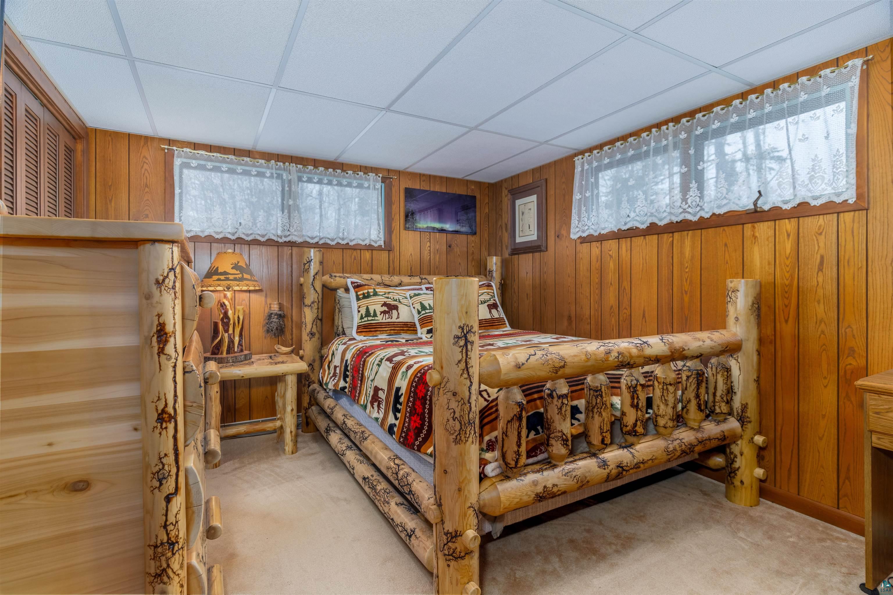 2641 Priest Point Road Ely, MN 55731 - Photo 20 of 38 Bedroom featuring light colored carpet, wooden walls, and a paneled ceiling