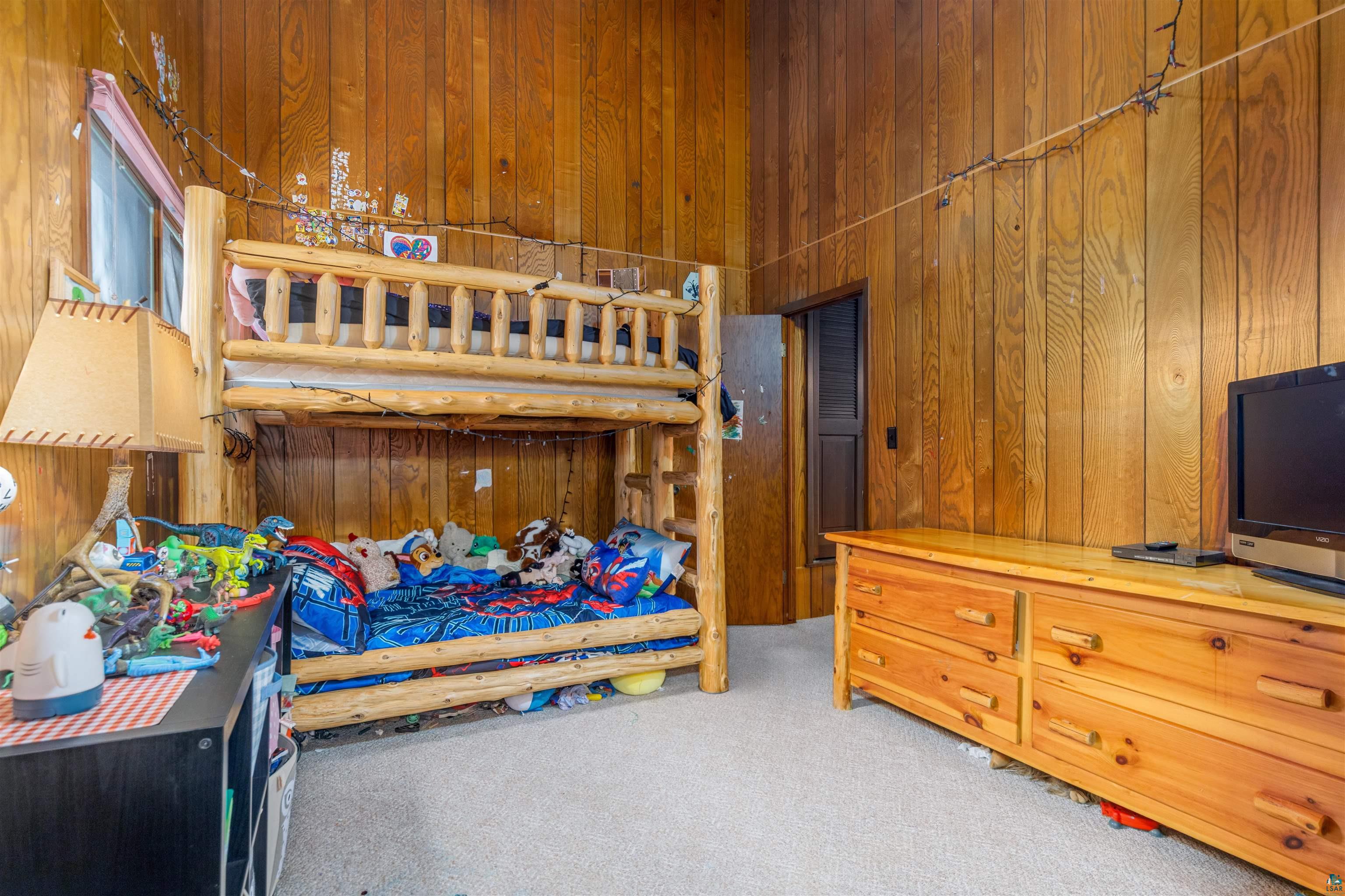 2641 Priest Point Road Ely, MN 55731 - Photo 22 of 38 Bedroom with wood walls, light carpet, and a high ceiling