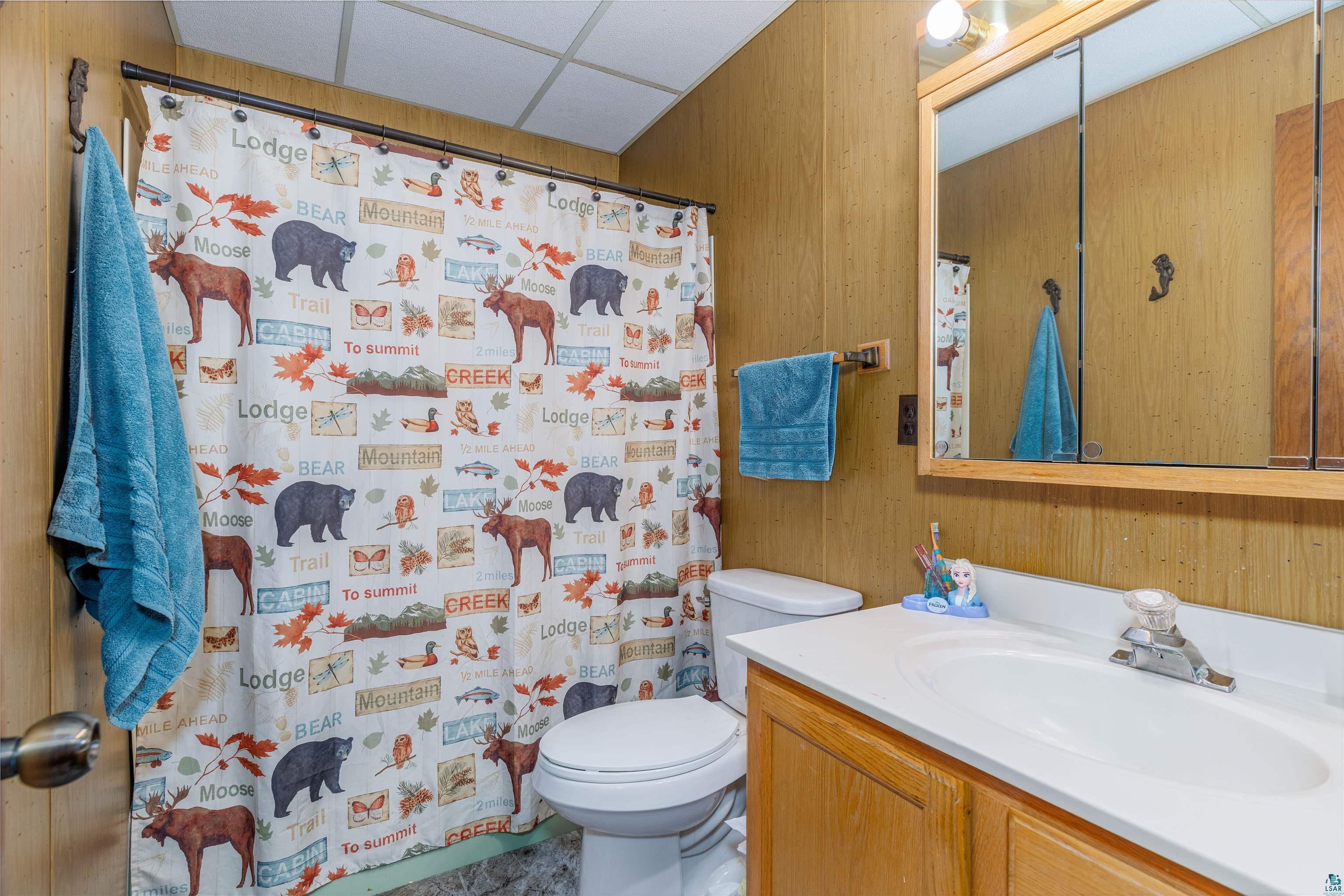 2641 Priest Point Road Ely, MN 55731 - Photo 31 of 38 Full bath with wood walls, vanity, a shower with shower curtain, and a drop ceiling