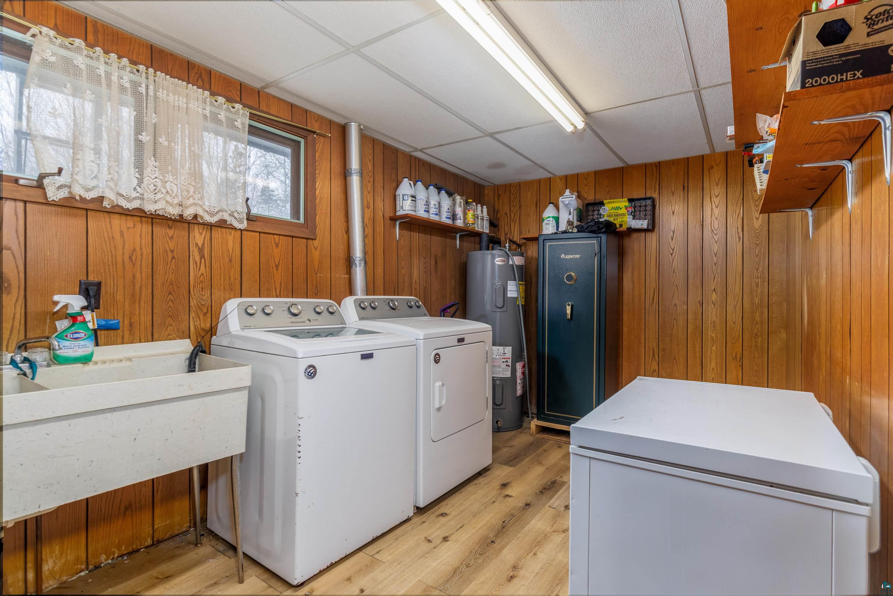2641 Priest Point Road Ely, MN 55731 - Photo 35 of 38 Laundry area featuring light wood-style flooring, separate washer and dryer, a paneled ceiling, water heater, and wooden walls