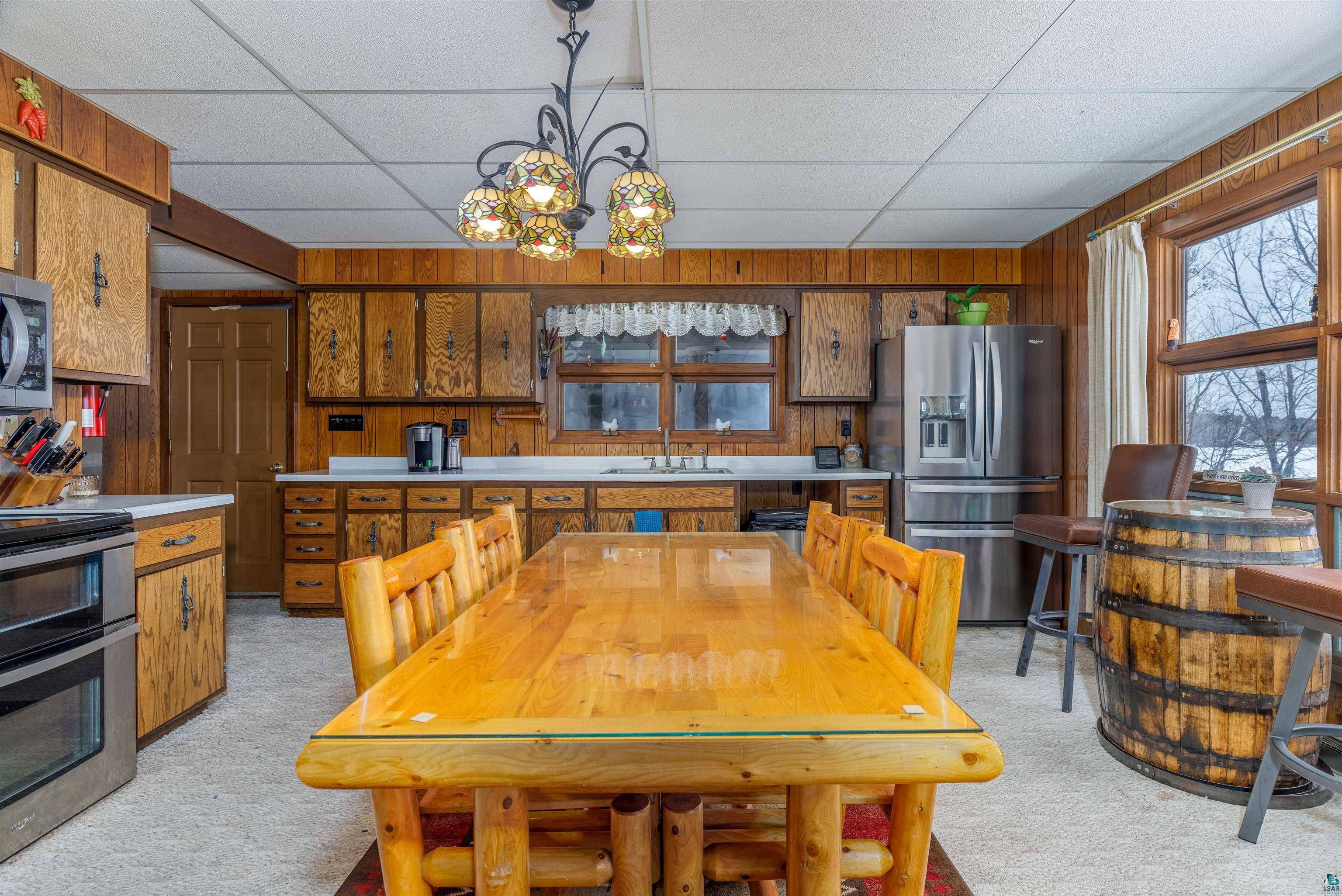 2641 Priest Point Road Ely, MN 55731 - Photo 9 of 38 Dining room featuring light carpet, hanging lights, wooden walls, and a drop ceiling