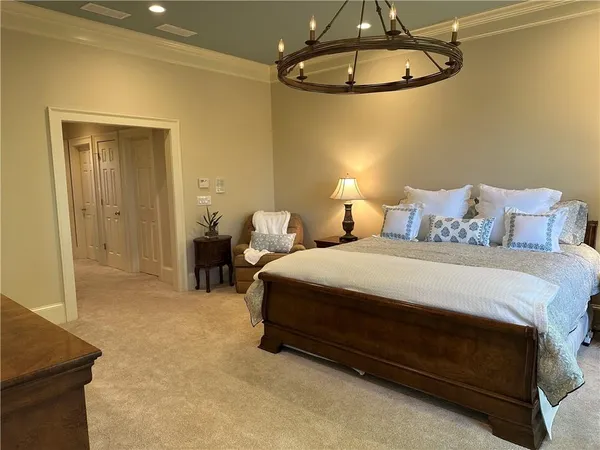 a bedroom with a bed a chair and flat screen tv