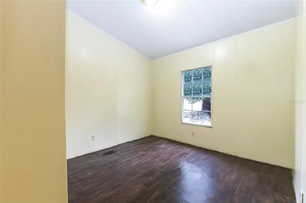 a view of an empty room with window and wooden floor