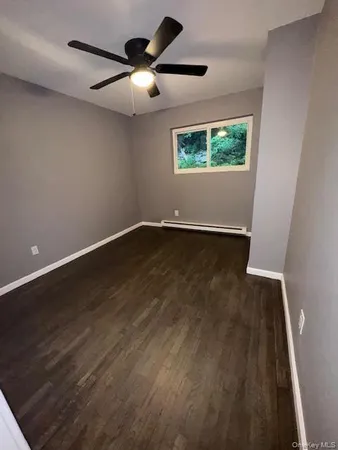 an empty room with wooden floor fan and window