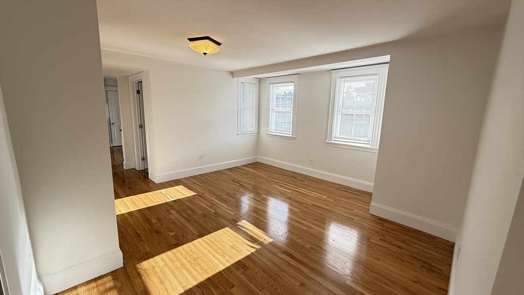 174 Boston Street, Unit 3 Boston, MA 02125 - Photo 4 of 13 a view of an empty room with wooden floor and a window