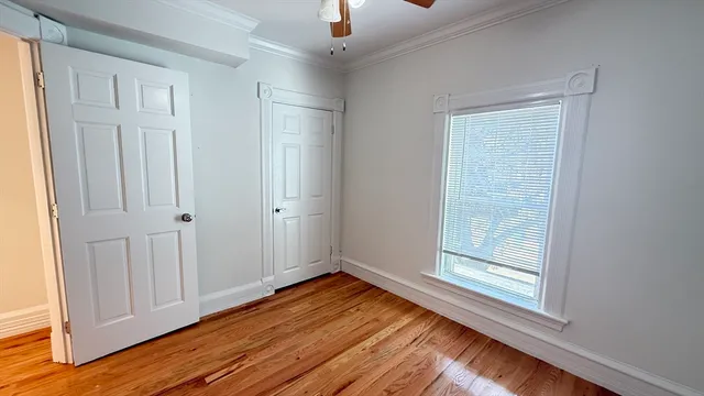 an empty room with wooden floor cabinet and windows