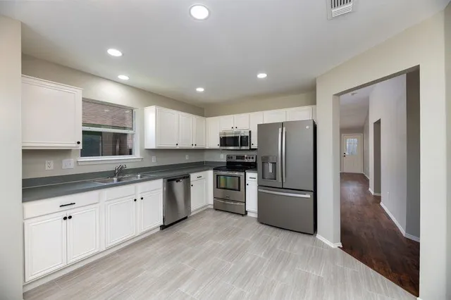 a kitchen with granite countertop a refrigerator and a stove top oven