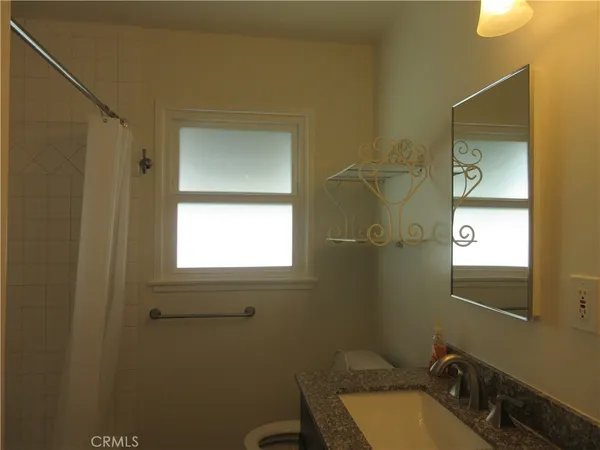 a bathroom with a granite countertop sink toilet and mirror