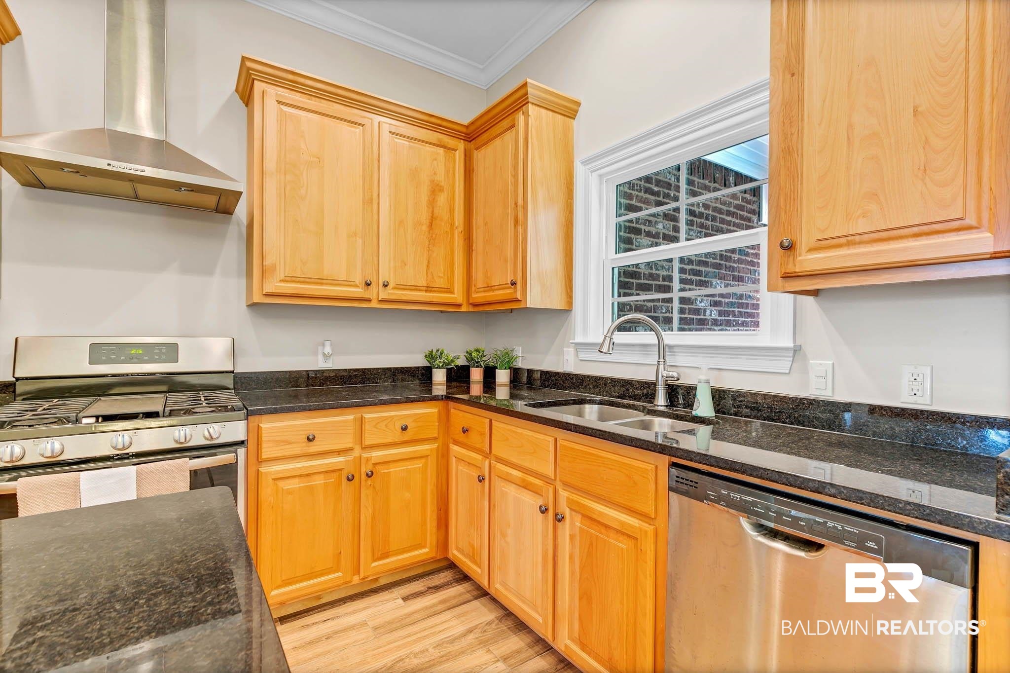 8145 Bay View Drive Foley, AL 36535 - Photo 19 of 81 Kitchen with appliances with stainless steel finishes, wall chimney range hood, crown molding, dark stone counters, and light wood-type flooring