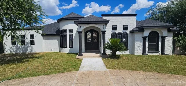 a view of a house with large windows and a small yard
