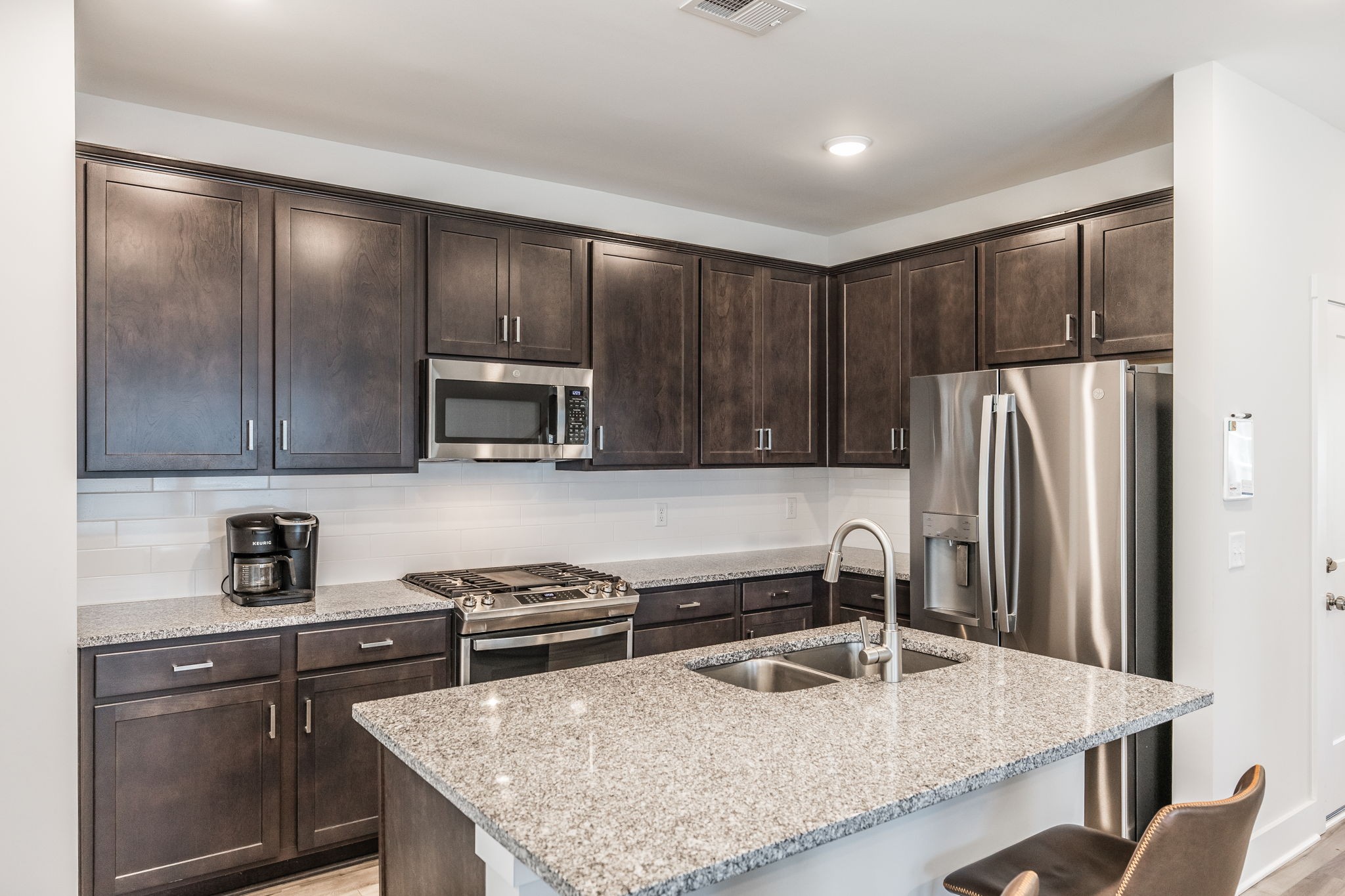 137 Cavalcade Loop Gallatin, TN 37066 - Photo 15 of 57 a kitchen with kitchen island granite countertop a refrigerator a stove and a sink with wooden cabinets