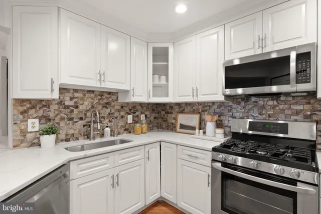 a kitchen with stainless steel appliances white cabinets and a stove top oven