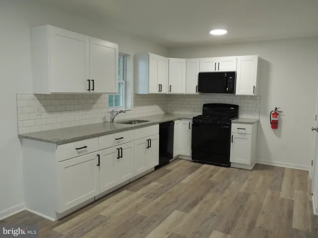 a kitchen with granite countertop white cabinets and black appliances