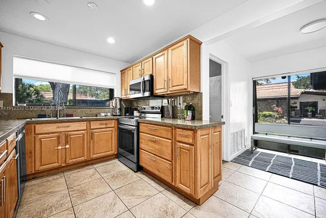 a kitchen with stainless steel appliances granite countertop a sink counter space cabinets and a large window
