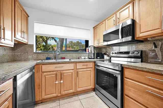 a kitchen with cabinets appliances a sink and a window