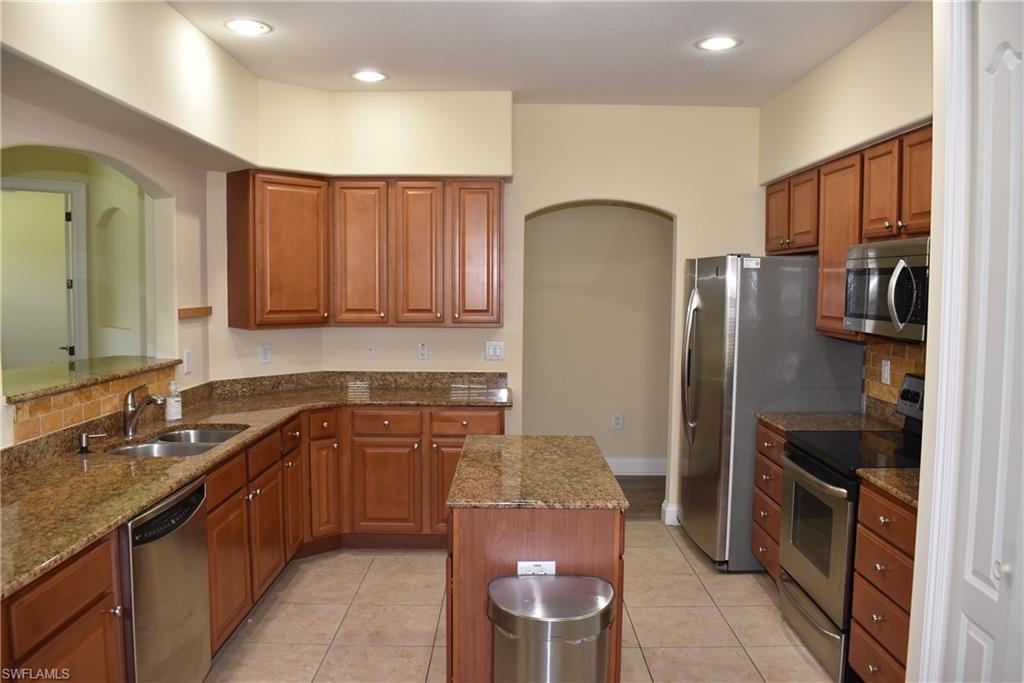 1311 Corso Palermo Court, Unit 2 Naples, FL 34105 - Photo 4 of 15 a kitchen with a refrigerator a sink and wooden cabinets