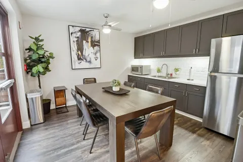 a kitchen with stainless steel appliances a table chairs refrigerator and wooden floor