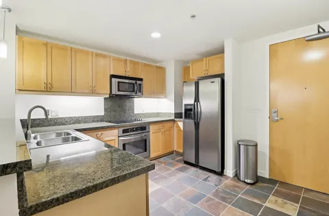 a kitchen with stainless steel appliances granite countertop a refrigerator a stove and a sink