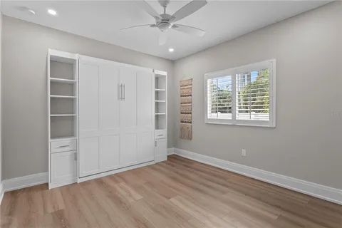 an empty room with wooden floor cabinet and windows
