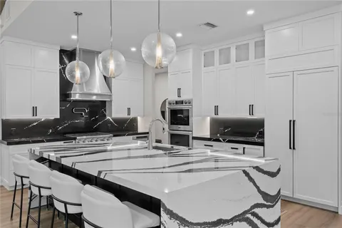 a kitchen with stainless steel appliances kitchen island granite countertop a table chairs and a stove