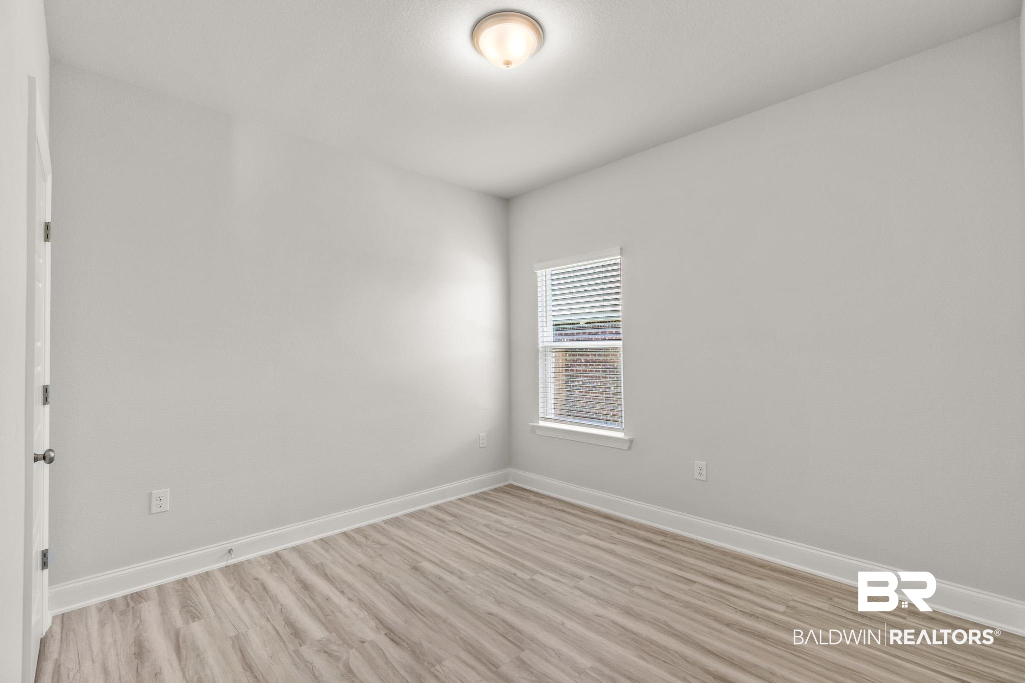 32125 Lyon Road Daphne, AL 36527 - Photo 31 of 70 Neutral-toned interior featuring wood-finish flooring, white baseboards, and a single window with blinds