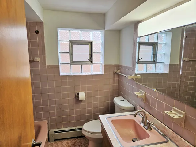 a bathroom with a sink mirror toilet and next to a window