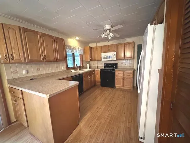 a kitchen with a refrigerator a sink dishwasher and a stove with wooden floor