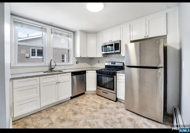 a kitchen with stainless steel appliances granite countertop a refrigerator sink stove microwave and cabinets