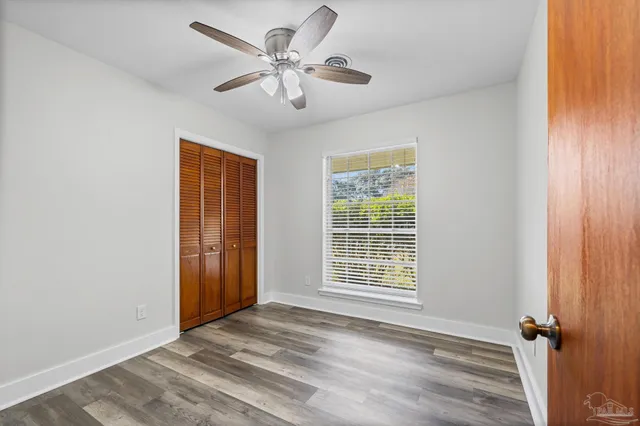 an empty room with wooden floor closet and windows