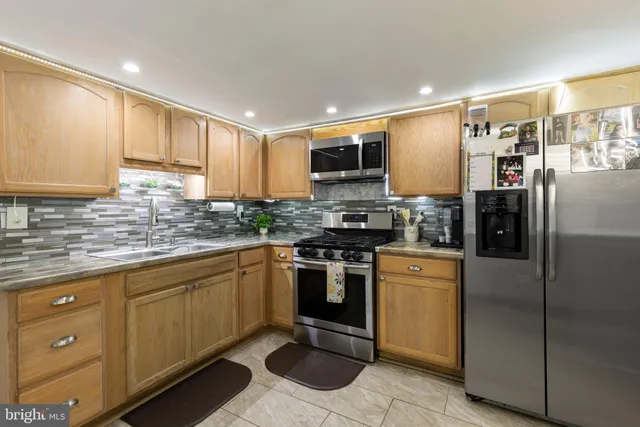 a kitchen with stainless steel appliances granite countertop a refrigerator a stove a sink and a microwave